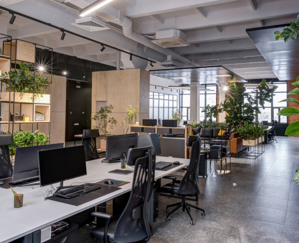 Modern loft-style office interior featuring open workstations, ergonomic chairs, greenery, and contemporary furniture—designed for collaborative and stylish workspaces.