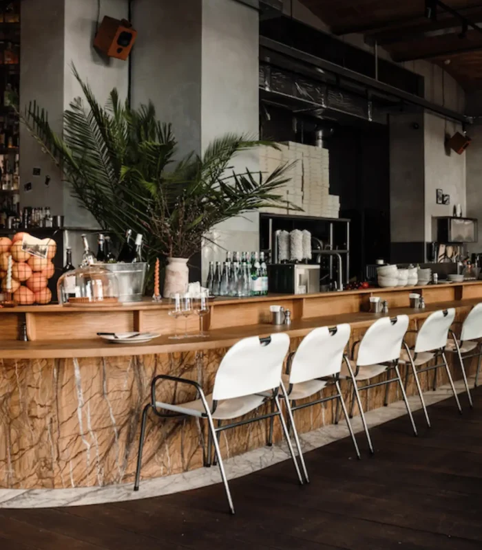 Contemporary restaurant interior featuring bar seating, wood tables, stylish chairs, and open shelving—highlighting modern FF&E for dining and hospitality spaces.
